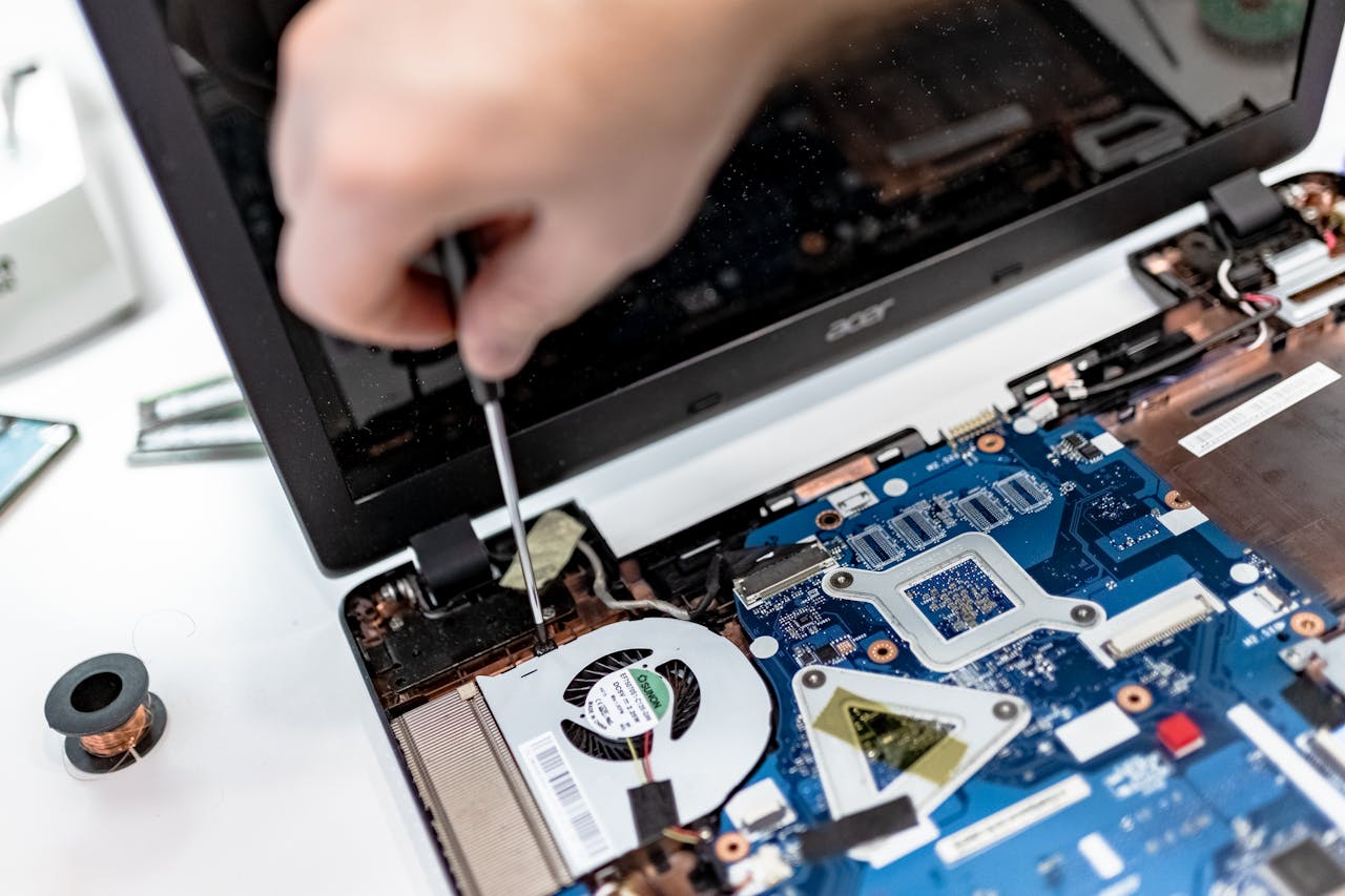 Home Technician repairing a laptop motherboard, focusing on electronic components.